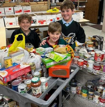 Hockey players from the Green Bay Youth Hockey Association pose with food drive donations.